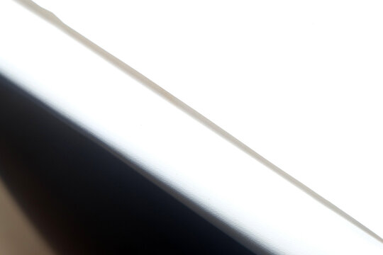 An overexposed close-up shot showing a sharp diagonal division between a bright white surface and a dark shadow beneath it.
