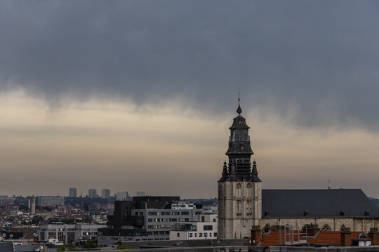Panoramic city view of Brussels with the historic Saint Jean Baptiste au Beguinage church under dramatic storm clouds