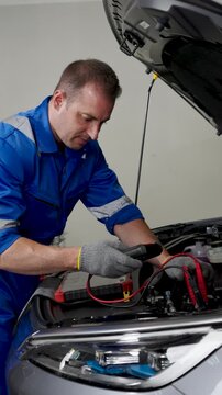 Close-Up Mechanic Hands Connecting Jumper Cables To Car Battery