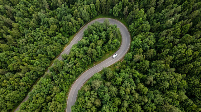 Aerial bird eye view of car driving on winding mountain road.