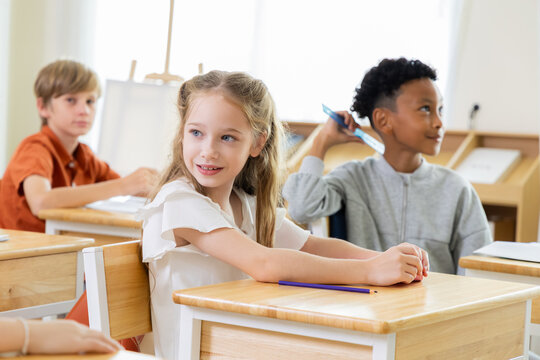 Young student listens in classroom beside classmates, expressing attention, confidence and positive learning during an elementary school lesson with active participation and curiosity.