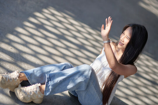 Young Woman Sitting on Ground with Sunlight and Shadows Creating Patterns