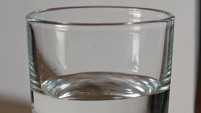 Dripping tap filling glass with fresh pure water, a close-up highlighting resource conservation, water scarcity, and leaking faucet repair issues for plumbing services