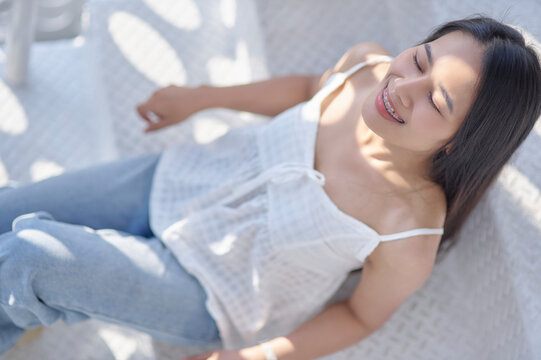 Relaxed Woman Enjoying Sunlight in Cozy Indoor Space