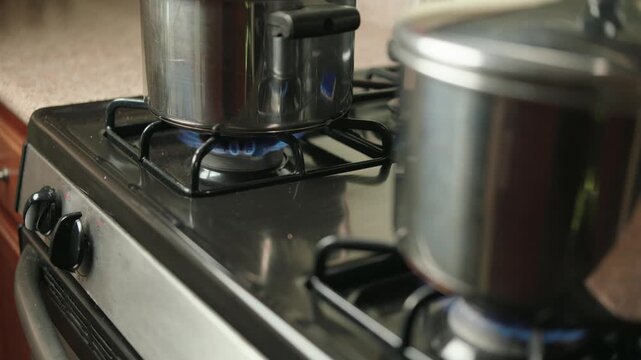 Two stainless steel pots cooking on a gas stove