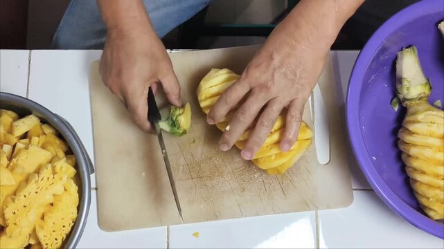 Top View cutting the pineapple into small pieces to put into the juicer.