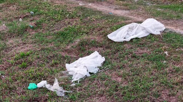 White fabric and plastic litter scattered on grassy field.