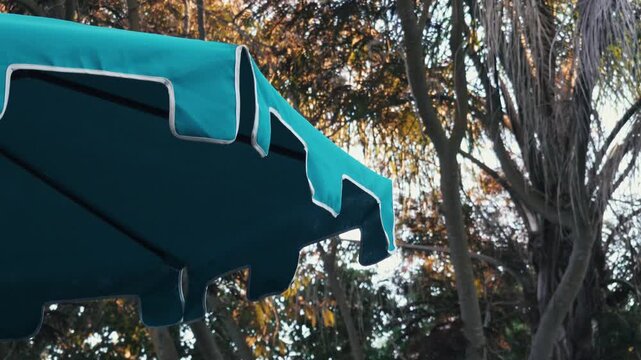 A teal patio umbrella stands in a garden