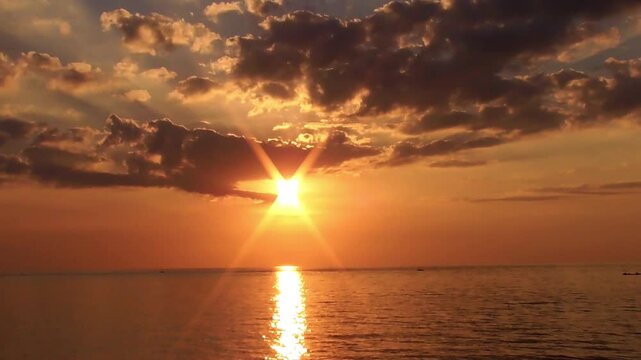 Golden sunset over a calm sea with a small fishing boat silhouetted against the glowing horizon, creating a peaceful and scenic coastal landscape