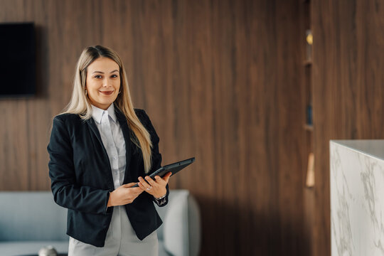 Professional businesswoman holding tablet smiling in office lobby