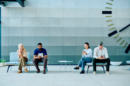 Business professionals and clients waiting in a contemporary office or clinic lobby, using digital devices and communicating