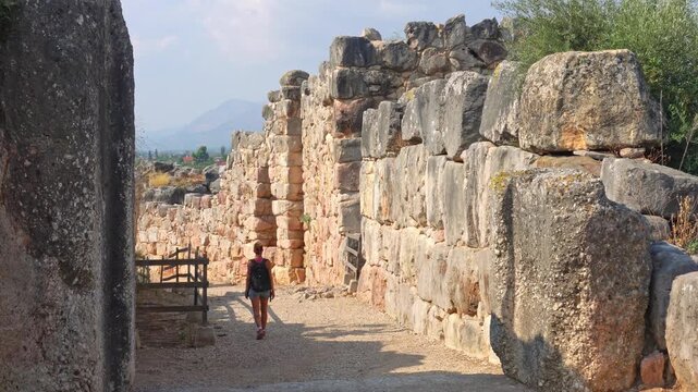Young woman walking through ancient Tiryns citadel ruins in Greece