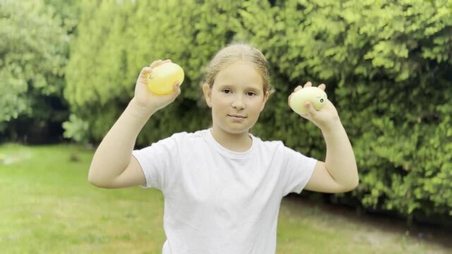 Young girl holding tennis balls in a park squishy Rainbow Mystery Bun