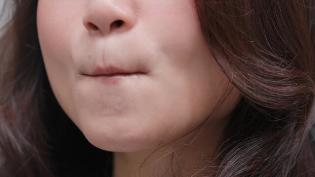 Close up shot of young Asian woman is smacking her lips to the camera and feeling beautiful.