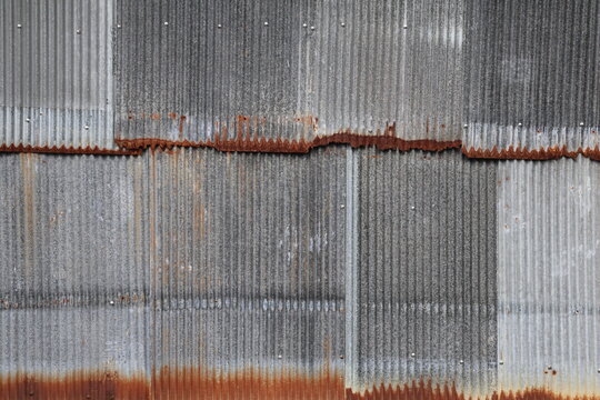 Artistic of old and rusty zinc sheet wall. Vintage style metal sheet roof texture. Pattern of old metal sheet. Rusting metal or siding. Corrosion of galvanized. Background and texture in retro concept
