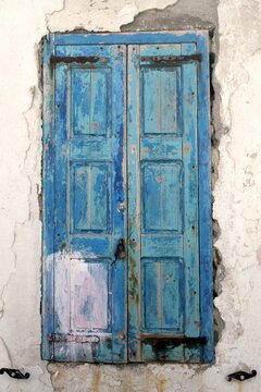 Vintage blue wooden window shutters on an old textured stone wall, close-up architectural detail.