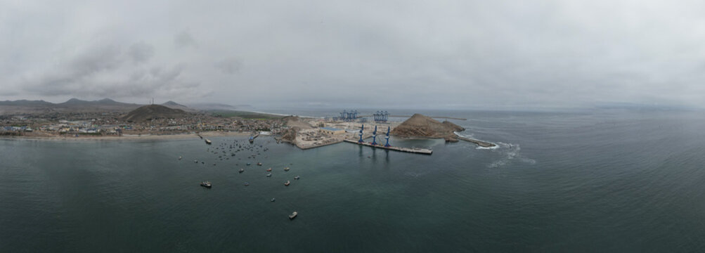 Chancay, Peru - 28 August 2024: Aerial view of the port of Chancay with industrial cranes, numerous small fishing boats in the bay, and the coastal landscape.
