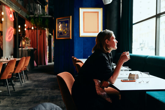 Side view of restaurant chef holding coffee cup while sitting at table