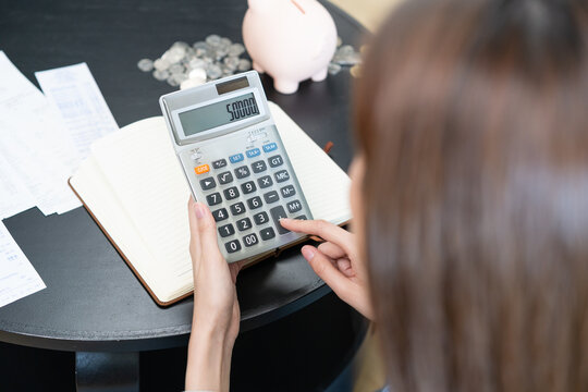 Saving money wealth concept, asian young business woman using calculator for calculate saving cost, cash finance planning to spend enough money on her income for save money, payment tax, investing.