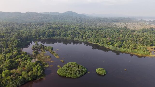 Wide angle aerial shot reveals a vast lake bordered by dense green forest