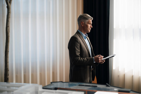 Thoughtful senior male entrepreneur holding documents at office