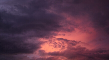 Obraz premium Dramatic sunset over a dark landscape with fiery clouds, atmospheric sky view, moody natural scenery, intense color contrast, evening atmosphere