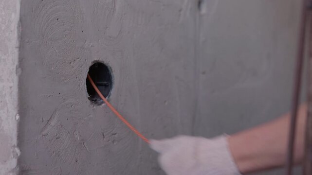 Electrician pulling electrical cable through conduit with fish tape