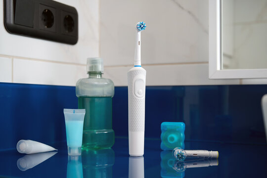 A set of electric toothbrush, dental floss, and mouthwash on the bathroom sink. A good choice.