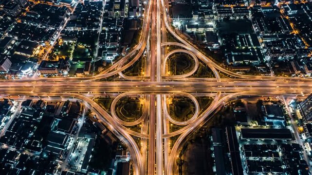 Direct overhead view of brightly lit highway intersection amidst urban blocks.