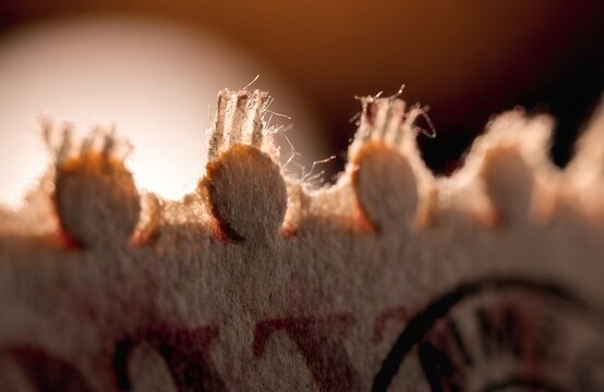 extreme macro of old postage stamp perforation edge faded ink print soft warm light paper grain texture