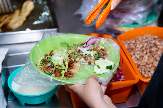 Close-up of hands preparing fresh street tacos with meat, onion and cilantro