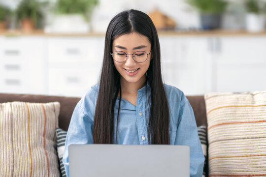 Happy Asian woman wearing glasses using laptop