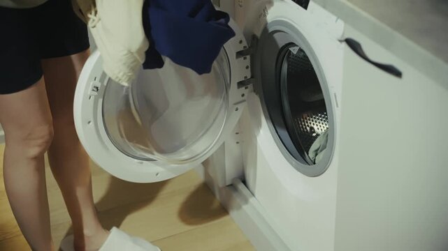 Person Loading Dirty Clothes Into Washing Machine.  Housekeeper Doing Laundry At Home. Domestic Chores