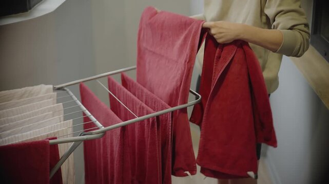Woman Hanging Towels On Metal Clothes Dryer Rack. Daily Housework 