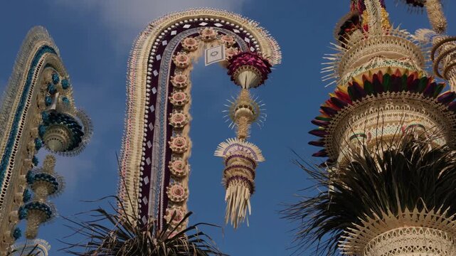 Traditional Balinese Penjor bamboo poles decorated for Galungan festival against blue sky, Bali, Indonesia