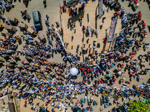 Zaria City, Kaduna, Nigeria - 28 October 2025: Aerial view of a bustling market in Zaria City with a dense crowd of people, numerous parked motorcycles, and street vendors.