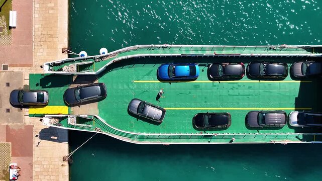 Ferry transports cars across water in clear weather near marina in busy harbor area