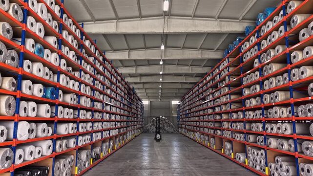 Yarn bobbins are stored on high shelves inside a textile warehouse with forklift operation. This video frame shows stock management, raw material storage, logistics, and industrial warehouse layout.