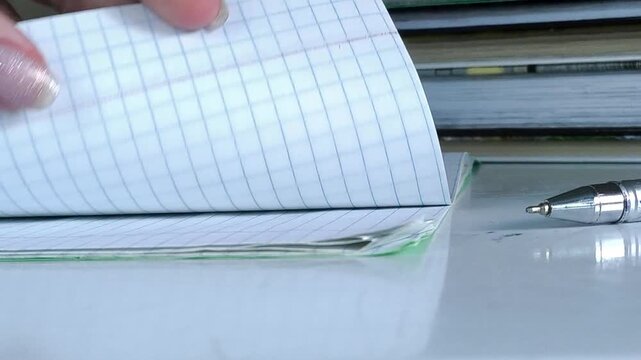 Student turning notebook page and starting to write, education, learning process and academic year concept.