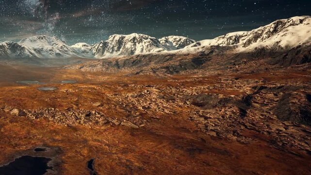 Mountains rise in the background against a clear night sky filled with stars. The terrain is brown and rocky, with some lakes visible. The view showcases natures beauty in a remote area.