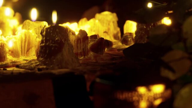 Warm light shines on various crystal formations and candles in a dimly lit space. People enjoy the cozy atmosphere during a gathering late in the evening.