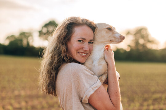Woman hugging dog in golden hour field