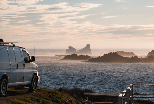 Camper van parked on a coastal cliff watching an iceberg