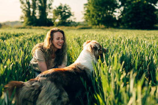 Woman smiling with australian shepherd dog in field