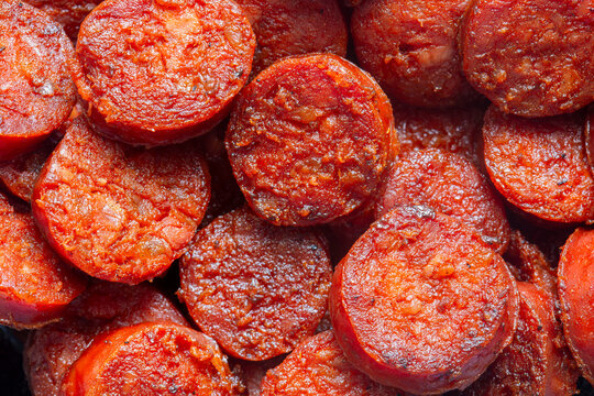 Spicy traditional sliced fried Spanish chorizo sausage background backdrop. Traditional Spanish food concept.