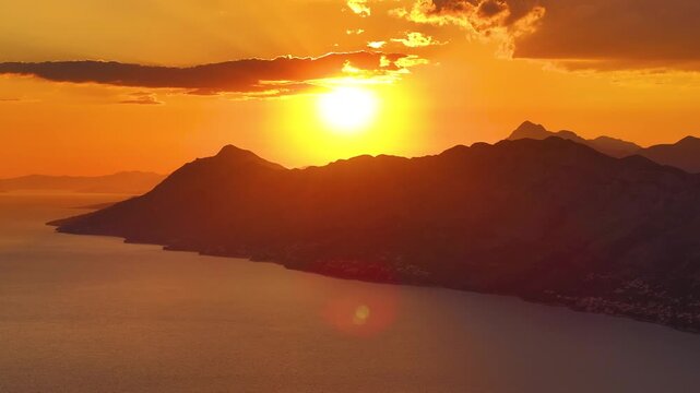 Sunset over mountains and water at coastal location with silhouetted landforms