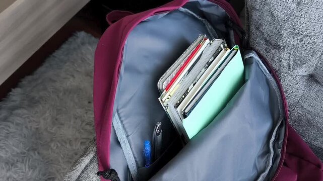 Open backpack with books and pens on chair, back to school concept, preparation for new academic year, education and studying.
