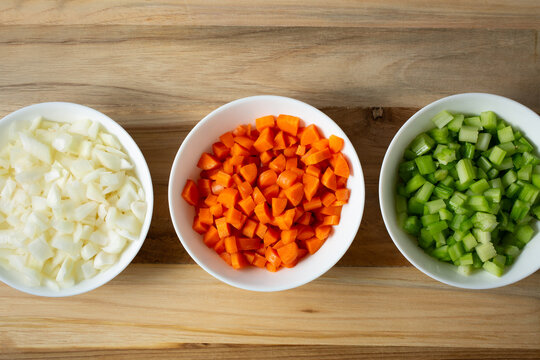 A view of some bowls of raw chopped mirepoix ingredients.