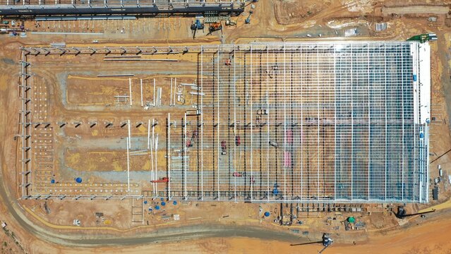 Industrial Construction Site: An aerial view showcases the vast scale of a modern industrial construction site, with steel framework and foundation being laid for a large structure.