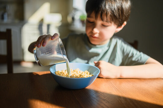 Pouring milk into a bowl of cereal at home in the morning